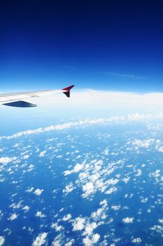 A wing of a flying jetliner in midair.