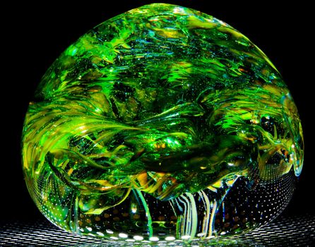 Unusual close up shot of blown glass ball (home made) in the form of a green forest or wood with overhanging leaves