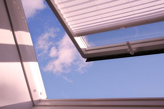 opened roof window with shutter and clouds