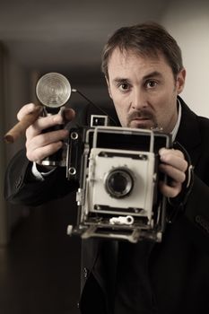 Photo of a retro 1940's style photographer taking a photo with an old 4x6 camera.  Desaturated and toned for retro feel.