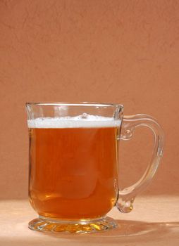 mug filled with beer, brown background