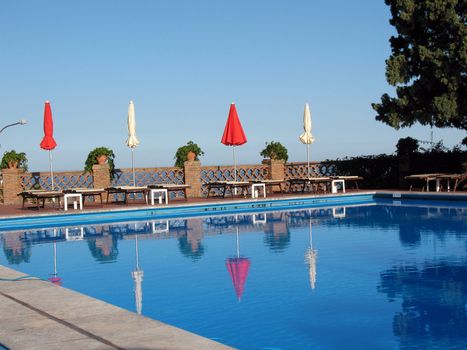 red and white umbrellas and tanning beds by the pool