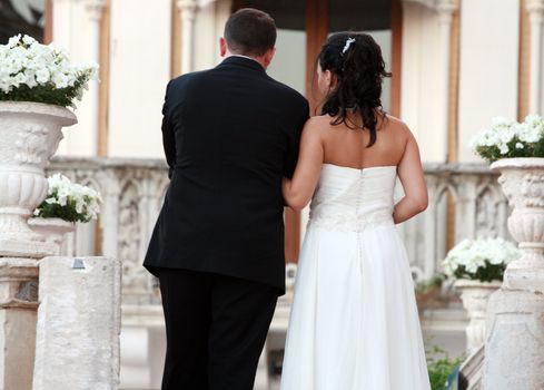 a just married couple on the steps of the church with flower arrangments 