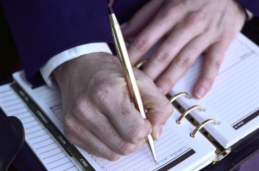Close up of Man's Hands Writing in Planner