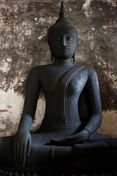 Black Buddha statue with the ancient wall