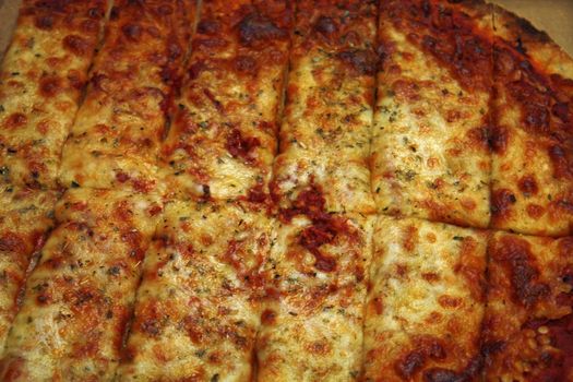 Cheese pizza cut into rectangle pieces ready to eat.
