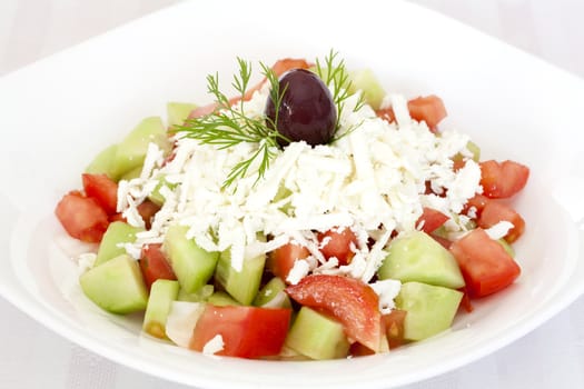 Fresh Greek salad with tomatoes, cucumber, onion, feta cheese and olive on top.