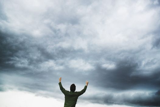 Man with Arms Raised with Cloudy Sky in Background