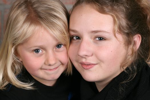 Two beautiful blond sisters holding one another close