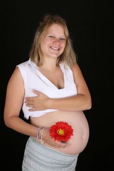 Heavily pregnant blond female against a black background