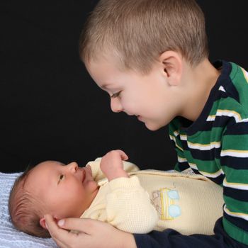 Blond boy with his newborn baby brother 
