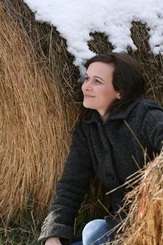 Beautiful brunette female leaning against hay bales