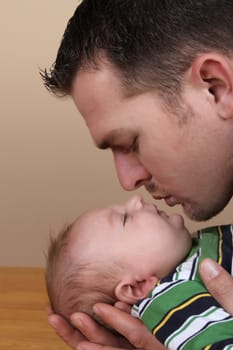 Attractive young father leaning in to kiss his baby boy