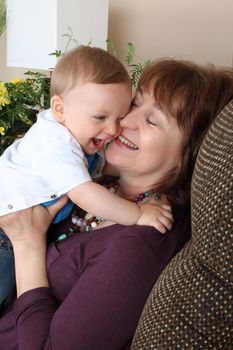 Beautiful blond baby boy sitting by his grandmother