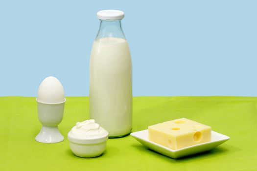 Fresh milk, cheese, curds and egg over blue background