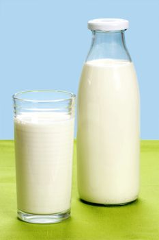 Glass of milk and milkbottle over blue background