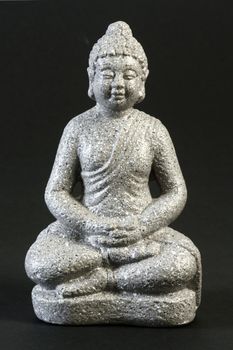 Buddha sculpture in lotus position over black background