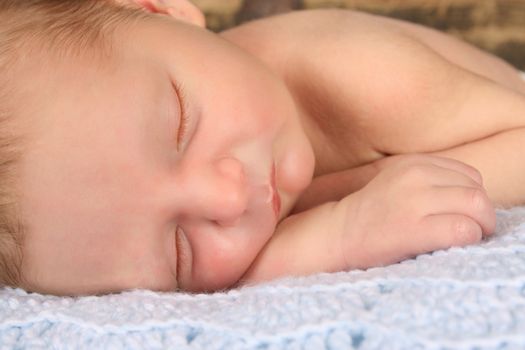 Newborn baby boy sleeping on a knitted blanket