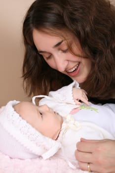 Beautiful brunette mother looking at her two month old baby girl 