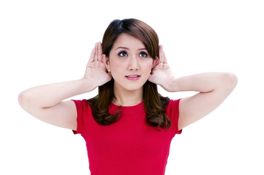 Portrait of a beautiful young woman with hands behind her ears against white background.