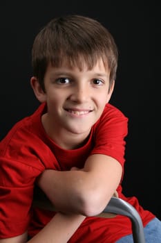 Brunette boy against a black background wearing red shirt