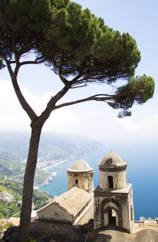 The Ravello garden offers a view of the two church towers, a tree and the Amalfi coast