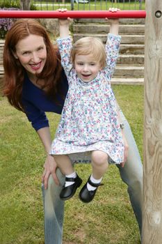 Redhead mother and blond daughter playing on the green park