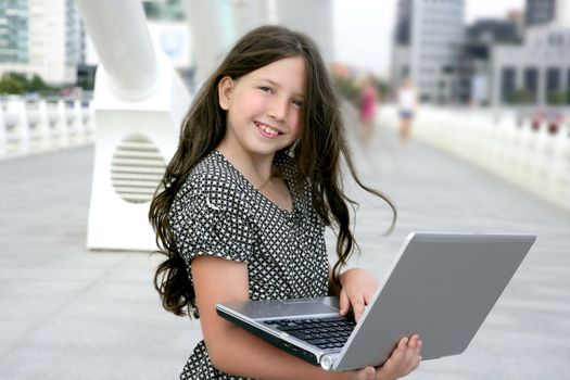 Beautiful little girl with laptop computer downtown city bridge