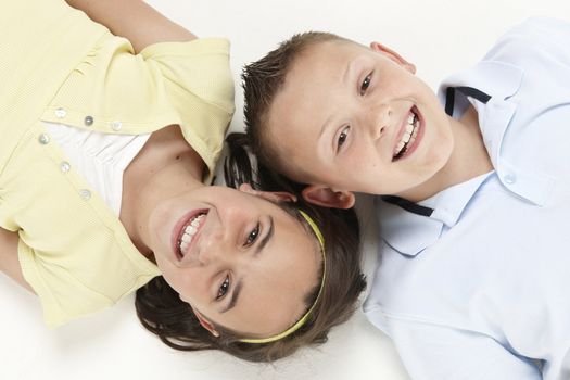 young boy and girl lying head to head looking up at camera