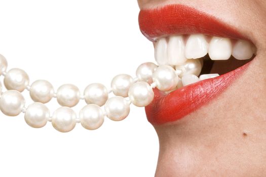 woman smiles showing white teeth, holding a pearly necklace in to the mouth, teeth care concept