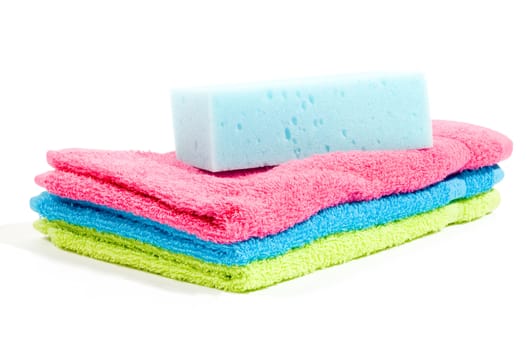 Multicolour towels stacked and body sponge isolated on white