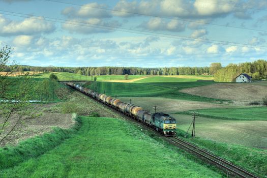 Freight train hauled by the diesel locomotive passing the fields
