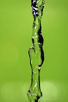 Water falling down, frozen in time with green background.