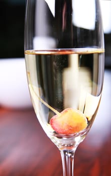 Close-up of a champagne glass on a mahoney table with a cherry in the glass