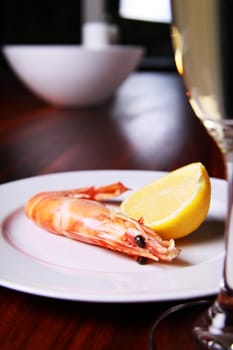 Giant shrimp on a plate, a glass of champagne and a lemmon