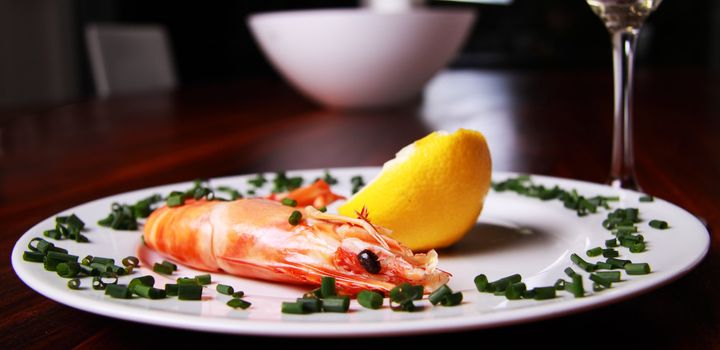 Giant shrimp on a plate, a glass of champagne and a lemmon