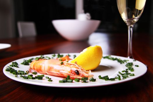 Giant shrimp on a plate, a glass of champagne and a lemmon