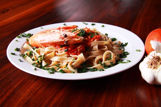 Shrimp pasta on a white plate served on a mahoney table