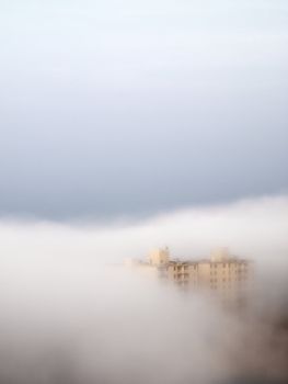 A single building barely visable through the heavy morning fog.