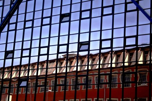 Business building with reflection of ancient house on windows.