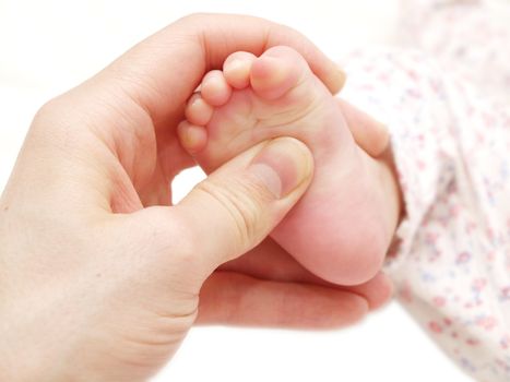 A baby receiving foot massage, towards white background