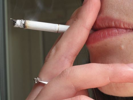 Woman is smoking thin sigarette, closeup photo                           