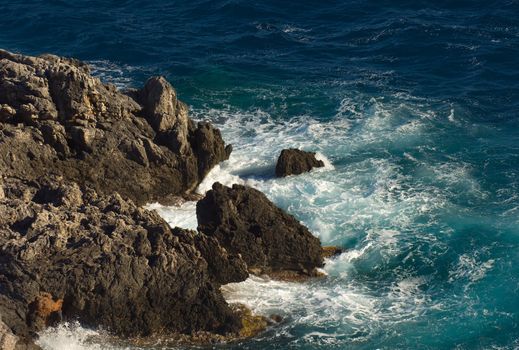 Image shows a stormy sea hitting a rocky cosatline, photographed from above