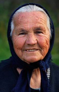 Image shows a portrait of an old Greek happy lady, wearing a scarf