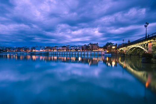 Dramatic panorama of Seville riverside at down and the Triana Bridge, the oldest bridge of Seville.