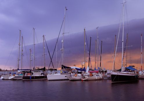 Image shows the marina in Kalamata, southern Greece, shot under a dusky sky. Image slightly blurred from sailboat movement.