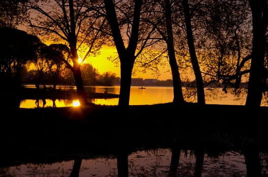 Romantic amazing colorful sunset reflects on river in early spring. Fishermen in the beautiful nature painting.