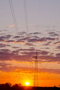High voltage electrical wires with sunrise in the background. Amazing view. Sun energy versus electricity.