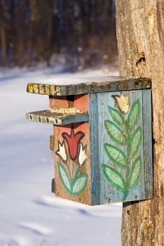 Beautiful painted nesting box in winter becomes feed for birds.