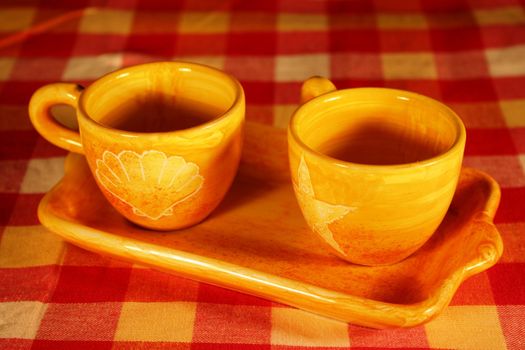 Yellow mugs on colored tablecloth